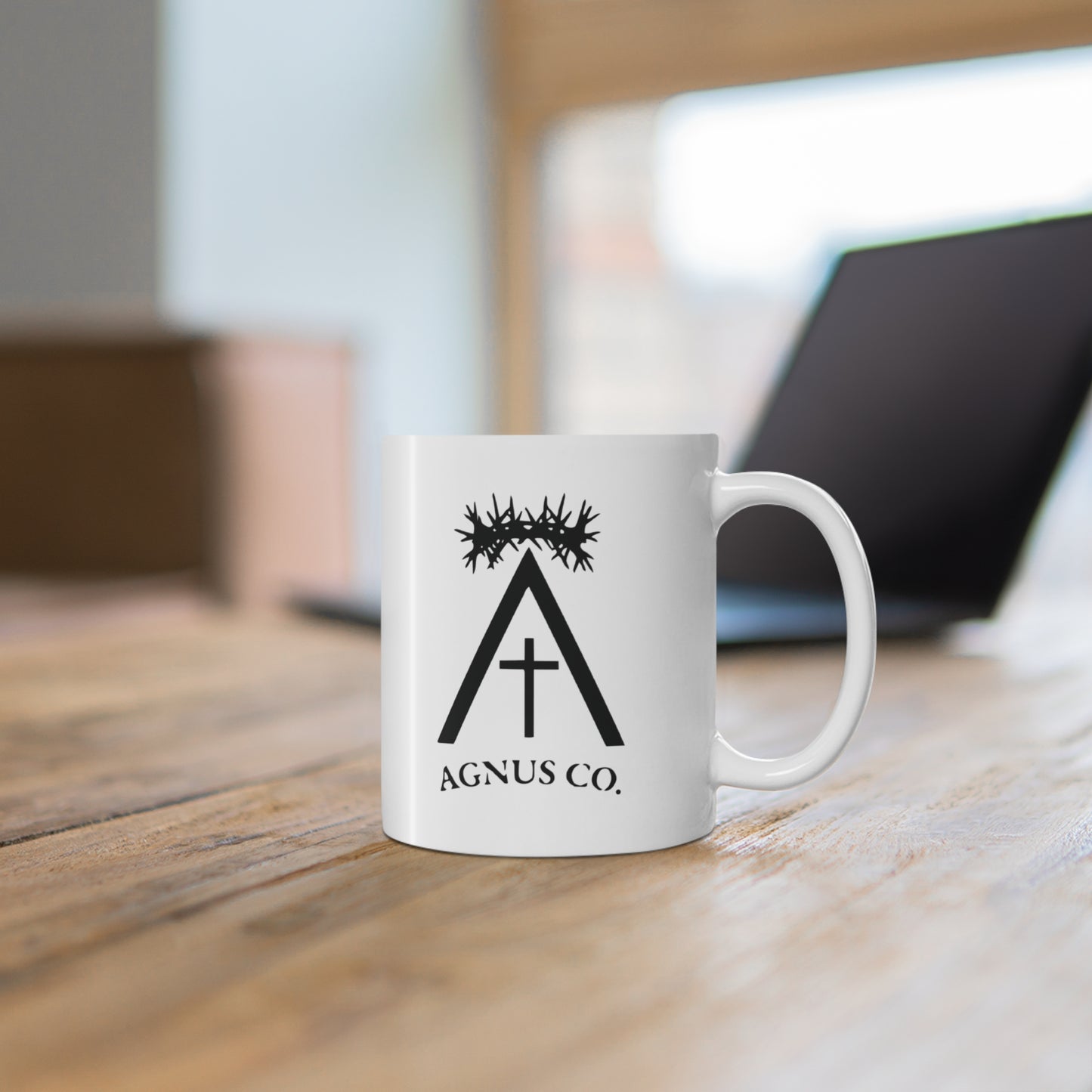 Agnus Co. Catholic coffee mug — lifestyle shot on wooden surface

